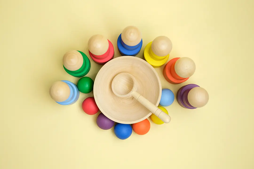 Buntes Holzspielzeug, das für die Entwicklung der Philosophie eines Kindes und der Montessori-Erziehung konzipiert wurde und auf gelbem Hintergrund präsentiert wird.