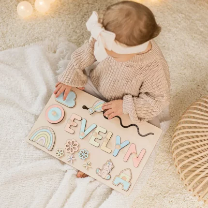 Ein Babymädchen spielt mit einem personalisierten Namenspuzzle aus Holz - ein einzigartiges und lehrreiches Geschenk, das Evelyn sagt.