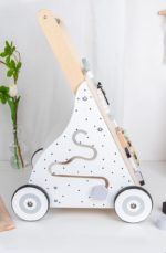 Ein Baby-Schiebe-Lauflernwagen - Multi-Aktivitäten - Pastellfarben steht auf einem Tisch neben einem Blumentopf.