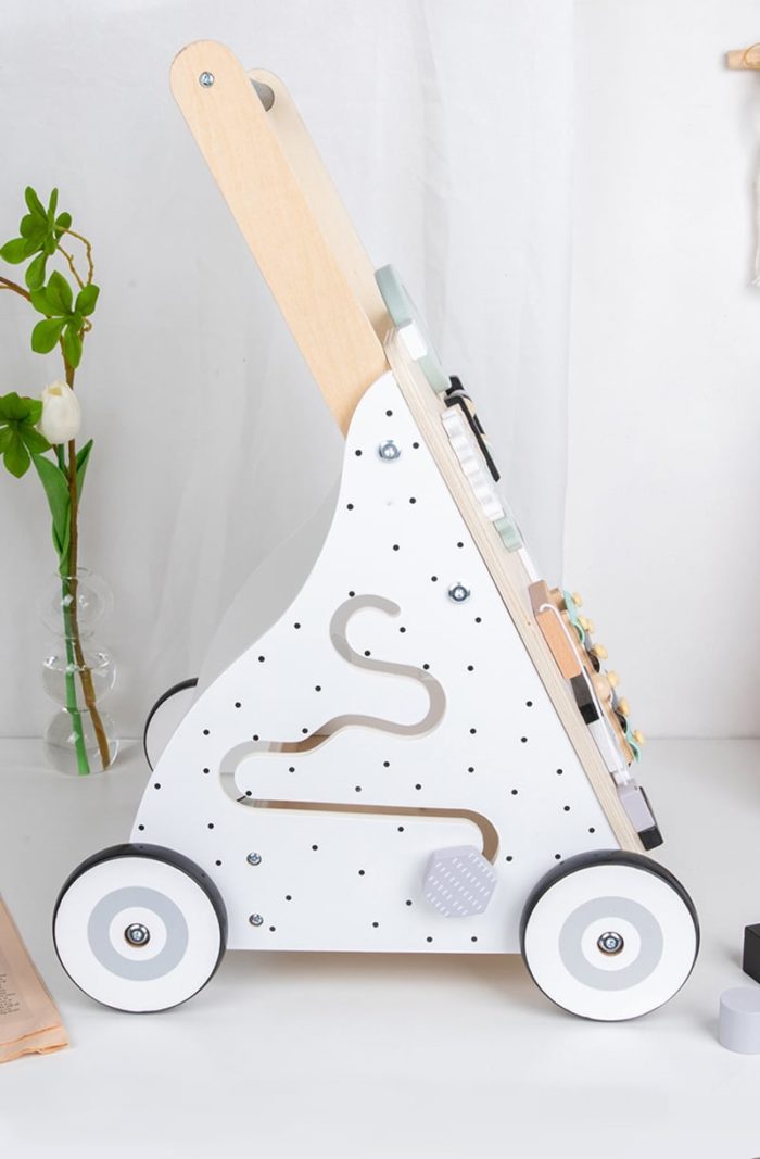 Ein Baby-Schiebe-Lauflernwagen - Multi-Aktivitäten - Pastellfarben steht auf einem Tisch neben einem Blumentopf.