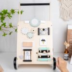 Ein Baby-Schiebe-Lauflernwagen - Multi-Aktivitäten - Pastellfarben vergnügt sich mit einem Multi-Aktivitäten-Wagen aus Holz.