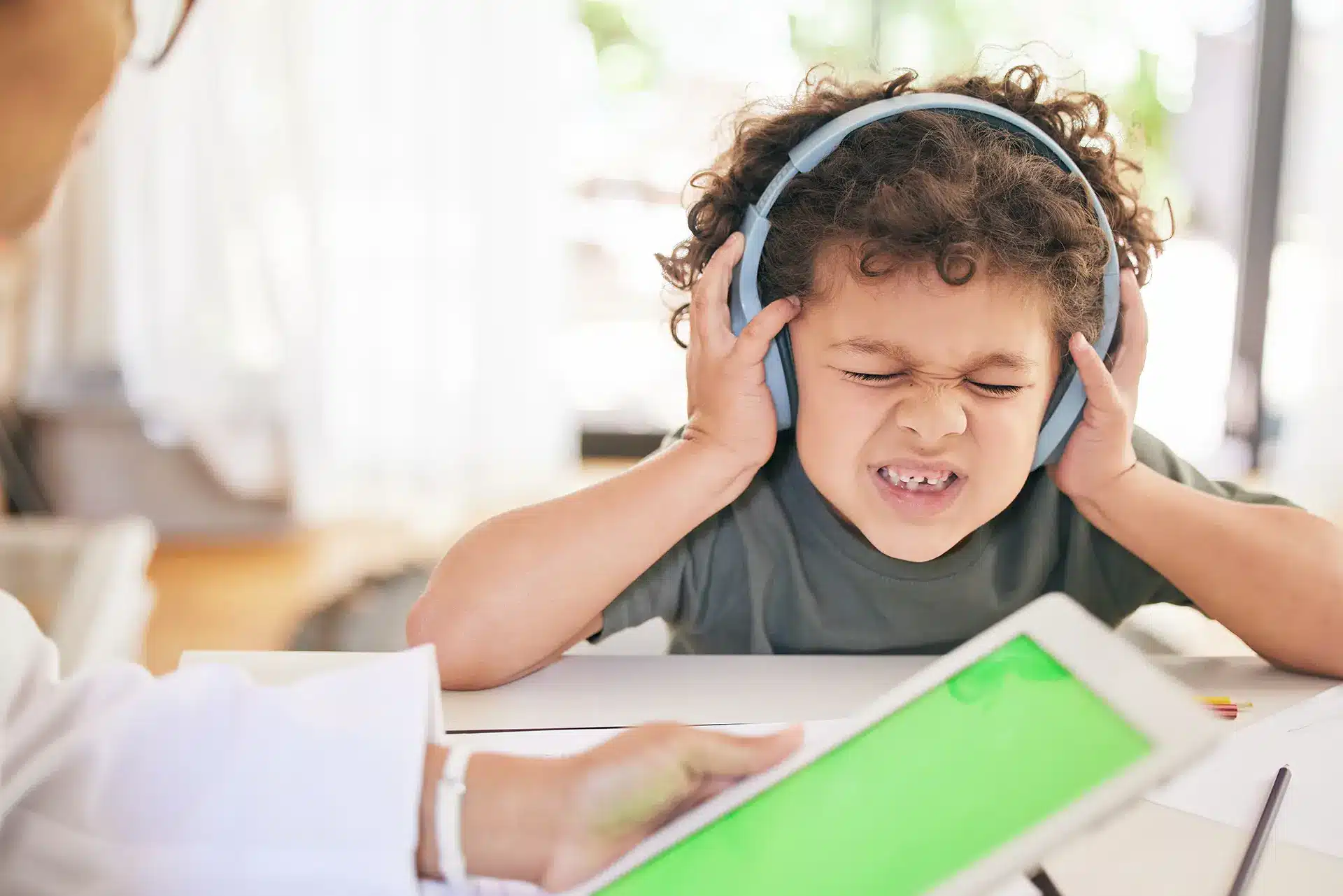 Ein Junge mit Kopfhörern und einem Tablet vor einem Arzt, der von der Montessori-Erziehung für Kinder mit Lernschwierigkeiten profitiert.
