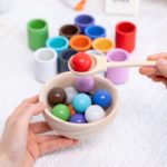 Eine Person, die ein Montessori Holzspielzeug Kugel und Sortierbecher zum Sortieren hält.