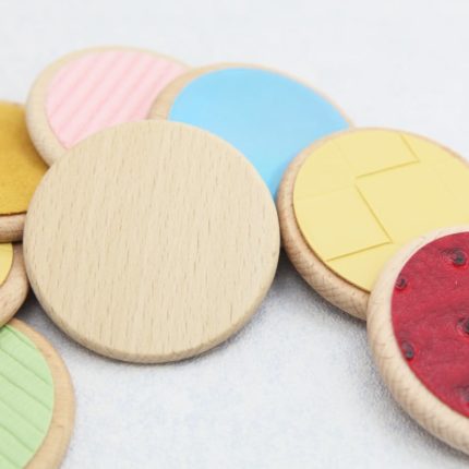 Ein Set von Sensorik-Pad-Spielzeug aus Holz mit verschiedenen bunten Formen.