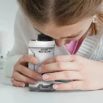 Kind Mädchen sieht ein Taschenmikroskop für Kinder - Tragbar - Vergrößert bis zu 120x.