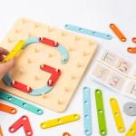 Kinderhand, die mit einer Sortierung von bunten geometrischen Formen und einem Puzzle "Montessori-Baukasten mit variablen Formen - Bild zum Kopieren" spielt.