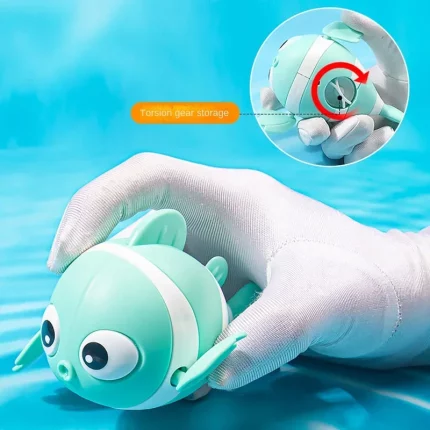 Eine Hand hält ein Badespielzeug Clownfisch, der im Wasser schwimmt.